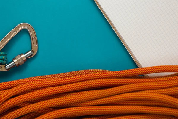 Notepad and climbing equipment on a blue background.