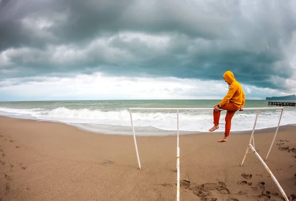 Un hombre se sienta en la playa en un día ventoso . — Foto de Stock