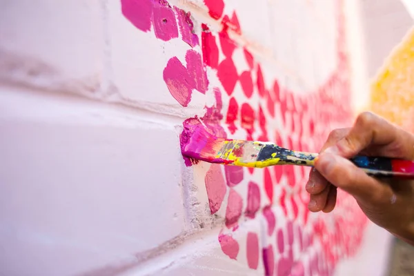 El artista dibuja en una pared de ladrillo . — Foto de Stock