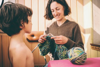 Bir kadın oğlu için bir kazak örme.