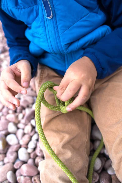 Ett barn lär sig att sticka en Knut från ett rep. — Stockfoto