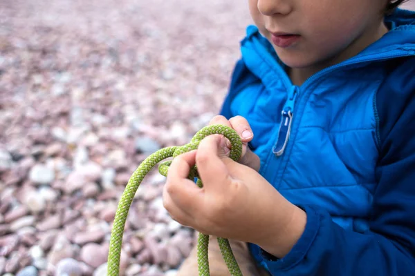 Ett barn lär sig att sticka en Knut från ett rep. — Stockfoto