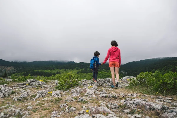 Ett barn med en ryggsäck går på en bergsstig. — Stockfoto