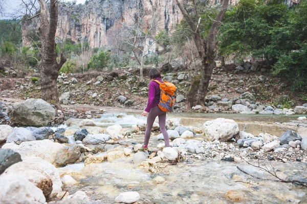 Mulher salta sobre o rio da montanha . — Fotografia de Stock