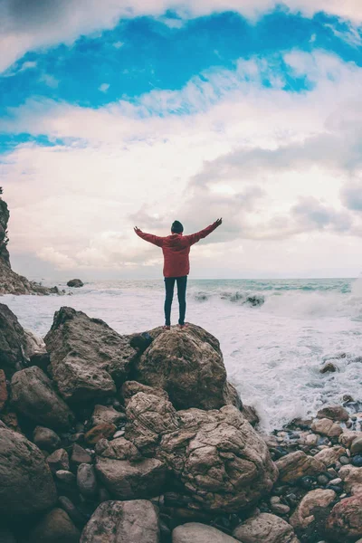 La chica está de pie en una piedra junto al mar . — Foto de Stock