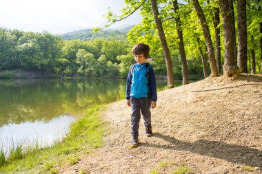 Gölde sırt çantası olan bir çocuk..