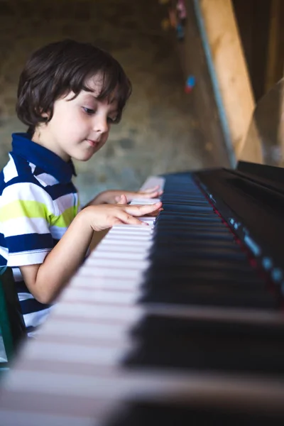 Un niño aprende a tocar el piano . — Foto de Stock