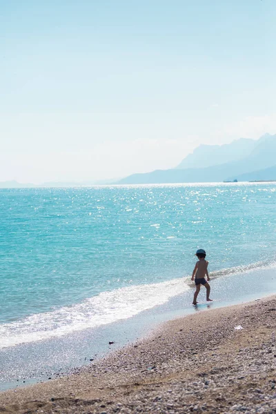 Ένα αγόρι στέκεται στην παραλία και κοιτάζει τη θάλασσα. — Φωτογραφία Αρχείου