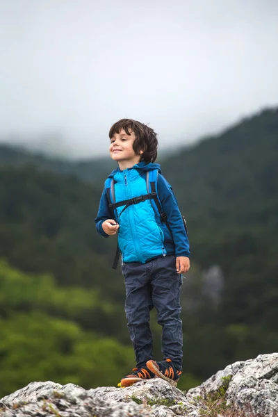 リュックサックを持った少年が山の上に立っている. — ストック写真