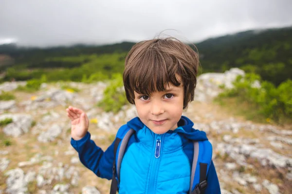 Ein Junge mit einem Rucksack auf den Gipfel des Berges geklettert und gibt fünf. — Stockfoto