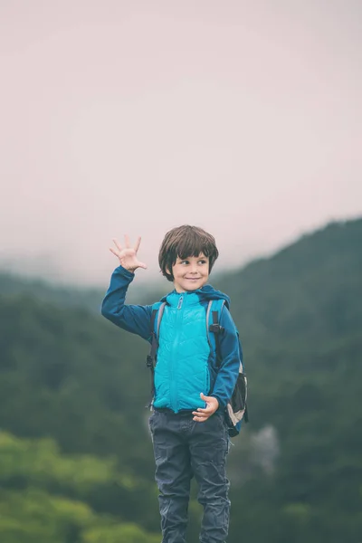 Мальчик с рюкзаком взобрался на вершину горы и дал пять . — стоковое фото