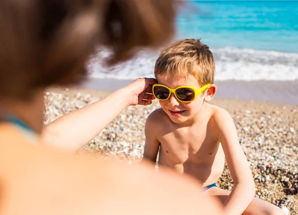 Güneş gözlüğü içinde bir çocuk sahilde oynuyor.