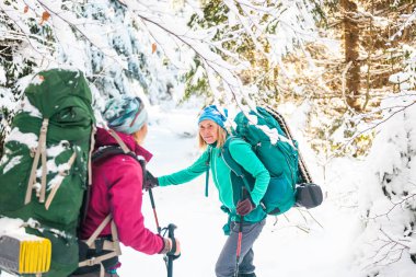 Bir kış yürüyüşünde iki gülümseyen kadın.