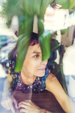 Gülümseyen kız bir kafede oturan ve pencereden dışarı bakıyor.