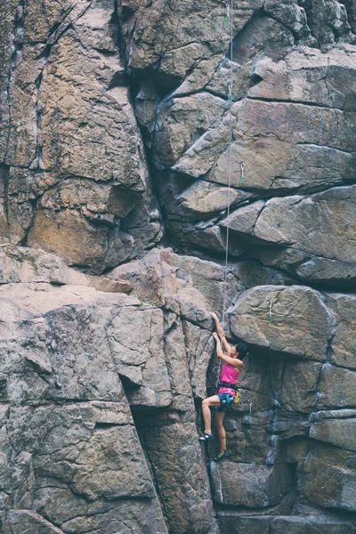 Het meisje klimt de graniet rots. — Stockfoto
