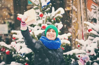 Süslü bir şehir ağacının yakınında Noel hediyesi olan kadın.