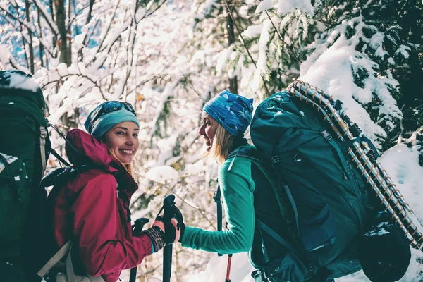 Bir kış yürüyüşünde iki gülümseyen kadın.