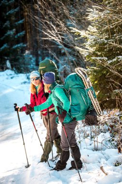Bir kış yürüyüşünde iki gülümseyen kadın.