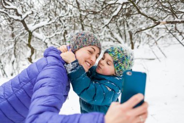 Bir kadın oğlu ile bir kış yürüyüşü bir selfie alır.