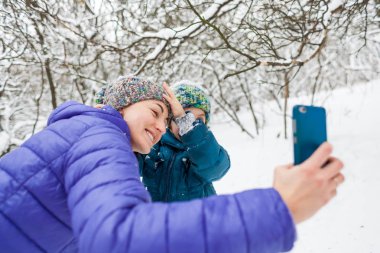 Bir kadın oğlu ile bir kış yürüyüşü bir selfie alır.