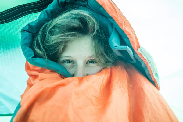 A girl peeks out of a sleeping bag. — Stok fotoğraf