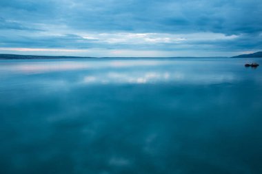 Deniz ve gökyüzü bulutlu gün batımında.