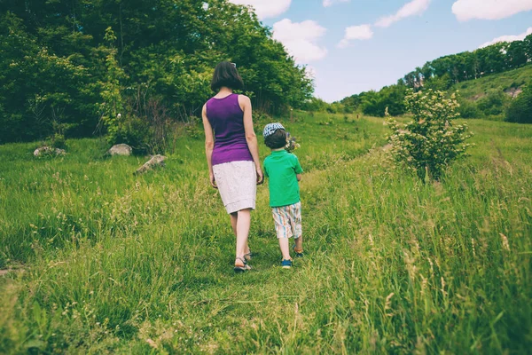 Una mujer con un niño está caminando en el prado . — Foto de Stock