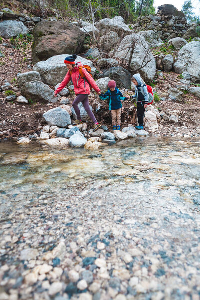 A woman with two children walks along a mountain river. 
