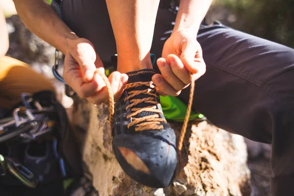 ロッククライマーは 登山靴やネクタイの靴を置きます 少女は石の上に座り 登山靴を履く ルートを克服するための準備 女性の手を閉じる — ストック写真
