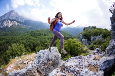 Sırt çantalı bir kadın taşların üzerinden atlıyor, bir kız dağlarda geziyor, aktif bir yaşam tarzı. Uçan Kadın, Türkiye 'nin pitoresk yerlerine Seyahat Et.