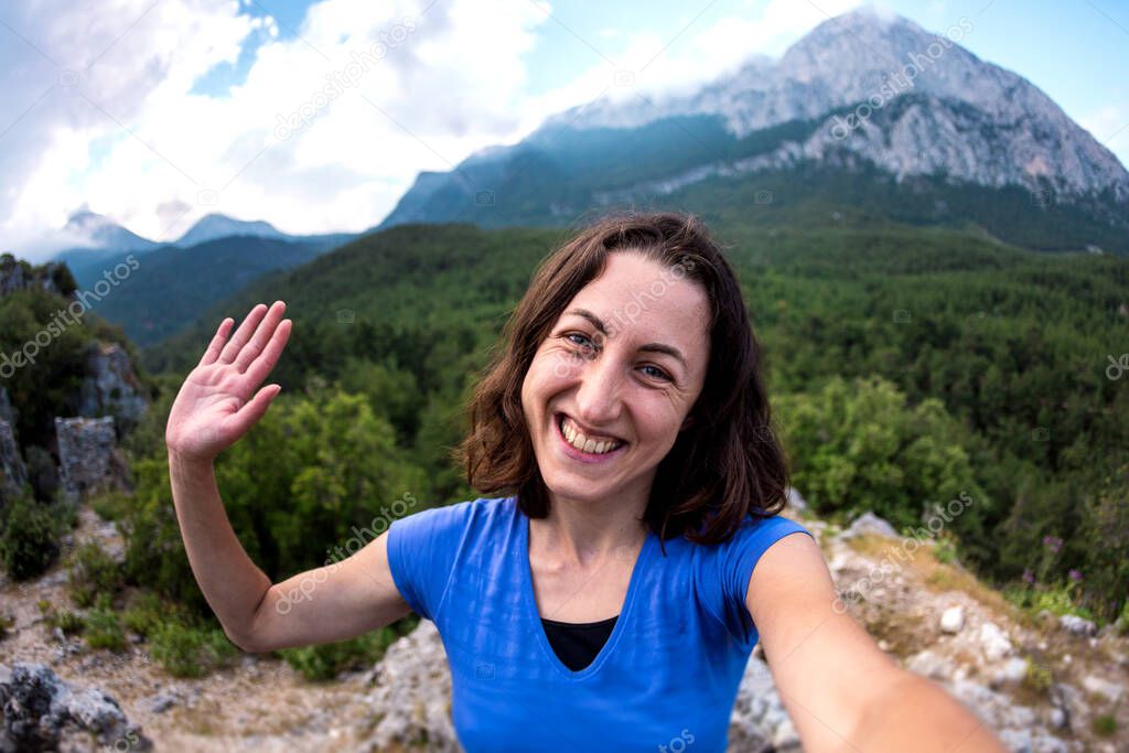 A woman takes a selfie on top of a mountain, a girl is photographed against a background of a mountain valley, a trip to the picturesque places of Turkey.