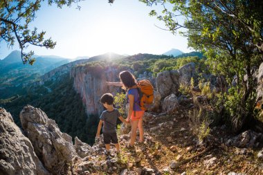 Oğlan ve annesi dağın tepesinde duruyorlar, bir kadın çocukla seyahat ediyor, çocuk annesiyle dağlara bakıyor, sırt çantalarıyla seyahat ediyor, yürüyüş yapıyor ve çocuklarla tırmanıyor..