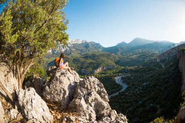 Sırt çantalı bir kadın dağın tepesinde oturur ve bir dağ vadisinin güzelliğine hayran kalır, Türkiye 'nin güzel yerlerine seyahat eder, hedefe ulaşır, güzel manzaraya ulaşır..