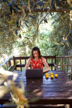 Kırmızı elbiseli bir kadın ahşap bir evin terasında çalışıyor, bir kız dizüstü bilgisayara bakıyor, uzaktan eğitim görüyor, serbest çalışan biri evin verandasında çalışıyor, karantina sırasında uzaktan kumandalı iş yapıyor..