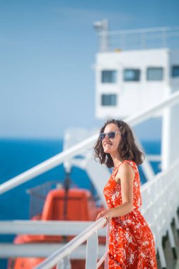 Bir kadın yolcu gemisinde yelken açıyor, bir kız bir gemide çitin yanında duruyor ve denize bakıyor, feribotla seyahat ediyor, yaz elbisesi giymiş bir esmer okyanusa hayran..