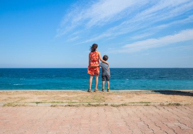 Çocuklu bir kadın gezinti güvertesinde durur ve denize bakar, annesiyle deniz kenarında yürüyüşe çıkmış bir çocuk, dinlenir ve çocuklarla seyahat eder, Türkiye 'de tatil yapar..