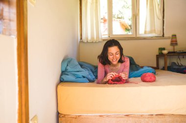 Kadın yatakta örgü örüyor, kadın elleri şapka örüyor, karantina sırasında yaratıcılıkla meşgul, el yapımı, favori ev hobisi....