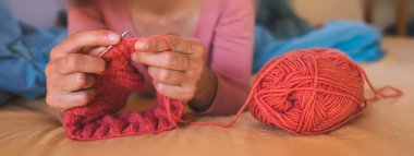 Kadın yatakta yatarken örgü örüyor, kadın elleri kapalı karantina, el yapımı, favori ev yapımı hobileri sırasında yaratıcılıkla meşgul..