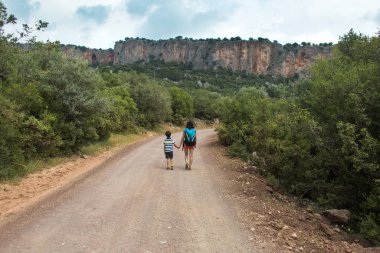Sırt çantalı bir kadın, bir çocuğu dağ yolunda elinden tutar ve bir çocuk annesiyle seyahat eder. Çocuklarla yürüyüş, Türkiye 'nin pitoresk yerlerine seyahat.