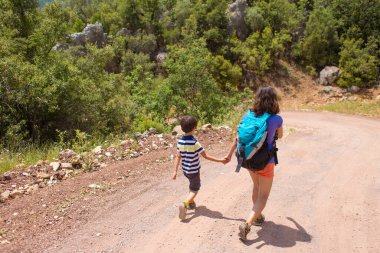 Sırt çantalı bir kadın, bir çocuğu dağ yolunda elinden tutar ve bir çocuk annesiyle seyahat eder. Çocuklarla yürüyüş, Türkiye 'nin pitoresk yerlerine seyahat.