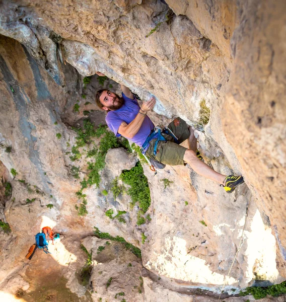 A strong man climbs a cliff, Climber overcomes a difficult climbing route on a natural terrain, Rock climbing in Turkey, Beautiful orange rock.