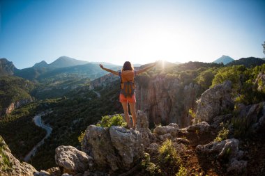 Sırt çantalı bir kadın, elleri havada bir dağın tepesinde durur ve bir vadinin güzelliğine hayran kalır, güzel yerlere seyahat eder, hedefe ulaşır, Türkiye 'nin güzel manzarasına..
