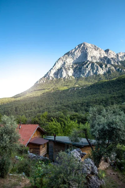 Small wooden houses at a climbing camp, Shelter for the traveler on the background of a high mountain, House with porch in a pomegranate garden, travel in Turkey