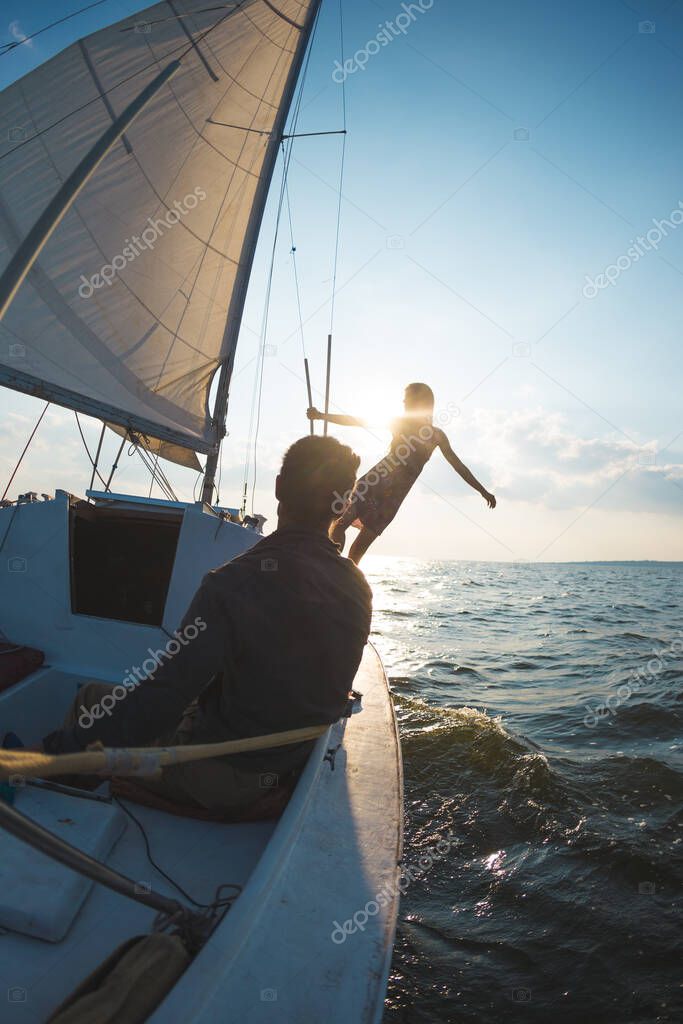 Romantic couple in love on sail boat at sunset under sunlight on yacht, A man and a woman are traveling on a sailing yacht.