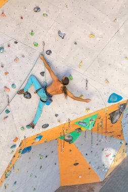 Bir adam tırmanma duvarına tırmanır, bir dağcı yapay arazi eğitimi alır, şehirde kaya tırmanışı yapar, güçlü bir adam, şehirde spor yapar, aşırı sporlarda güvenlidir..