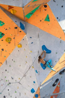 Bir adam tırmanma duvarına tırmanır, bir dağcı yapay arazi eğitimi alır, şehirde kaya tırmanışı yapar, güçlü bir adam, şehirde spor yapar, aşırı sporlarda güvenlidir..