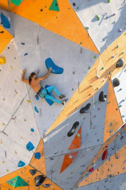 Bir adam tırmanma duvarına tırmanır, bir dağcı yapay arazi eğitimi alır, şehirde kaya tırmanışı yapar, güçlü bir adam, şehirde spor yapar, aşırı sporlarda güvenlidir..