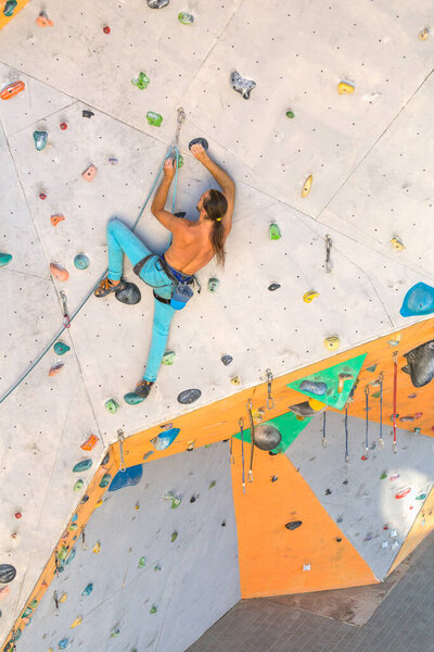 A man climbs a climbing wall, a climber is training on artificial terrain, rock climbing in the city, a strong man, sports in the city, safety in extreme sports.