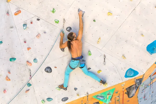 Bir adam tırmanma duvarına tırmanır, bir dağcı yapay arazi eğitimi alır, şehirde kaya tırmanışı yapar, güçlü bir adam, şehirde spor yapar, aşırı sporlarda güvenlidir..