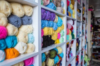 Dükkanda iplikle doldur. Örgü örmek için çok renkli iplikleri olan raflar. Renkli ipliğin arka planı. Toplar yakın plan çekimde. Dikiş için malzemeler. 
